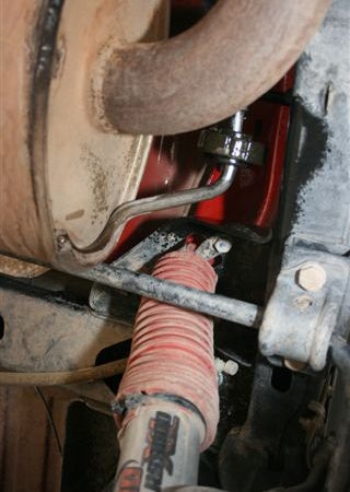 Using grommet pullers or a long pry bar, remove the passengers side muffler hanger from the rubber grommet. dB recommends soapy water; I used silicone spray to ease the grommet chores.